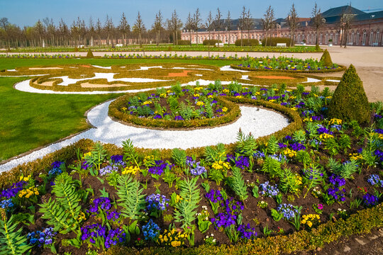Lovely close-up view of planting beds, created in geometric shapes, in the French formal garden of Schwetzingen Palace. In the background is one of the semi-circle curved outbuildings (Zirkelbauten).