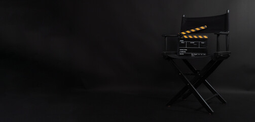 Obraz premium Black director chair. Yellow and black color Clapper board or movie slate on a chair with a black background.