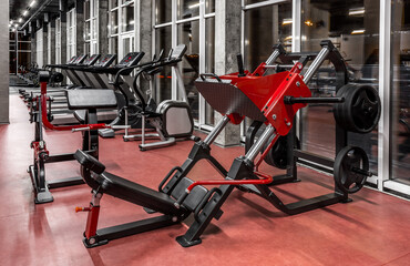 Exercise machines to strengthen the muscles of press, legs and back in spacious empty gym interior. Modern treadmills by the window. Sport, fitness