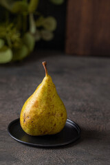 Conference Pear on dark background  i with green leaves branch  and cut board.Rustic style