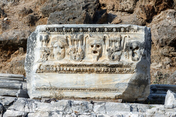 Fragment of marble decoration with mask bas-relief. Ruined ancient theater in Side, old antique...