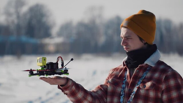 The guy launches the quadrocopter hands into the air. Shots in winter outside the city.
