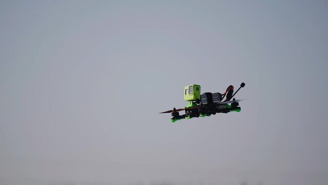 Slow-motion close-up of a drone flying over a snowy field. A camera is mounted on the quadcopter