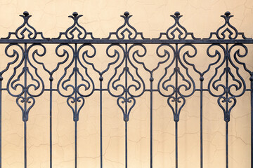 Ornate wrought iron fence against a cracked wall