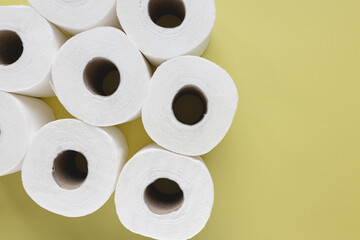 Fresh new white toilet paper rolls on yellow background. Personal hygiene and health issues concept. Top view, copy space