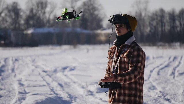 The guy catches the drone with his hand after completing the flight. On the guy's head is an fpv helmet. Shooting in winter