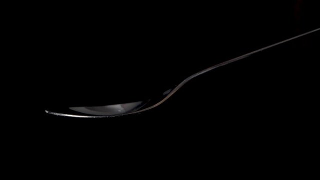 Pouring sea salt or on a spoon in slow motion, isolated on black background