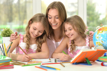 Teacher with two girls drawing together at art class