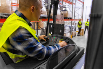 wholesale, logistic, loading, shipment and people concept - close up of man or worker operating forklift loader at warehouse