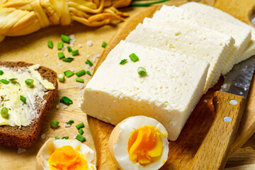 tasty lunch in rural style, healthy food - bread and butter sandwich, feta cheese, eggs, green leek and rye bread, cooked food on a white wooden boards