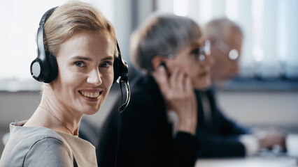 Smiling businesswoman in headset looking at camera in office