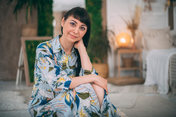 Fototapeta premium Portrait of a brunette girl in casual clothes in a relaxed pose. Cute young woman in a colorful dress in a positive good mood