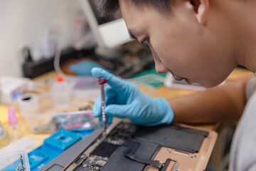 Phone repair concept a young male technician wearing a protective face mask in order to protect himself from the dust and germs during repairing an electric device