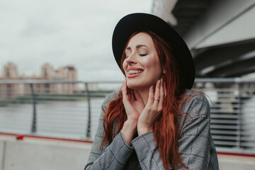 Fototapeta premium young woman with red hair outdoors in a coat and hat with braces