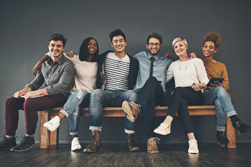 Colleagues that have become friends. Studio shot of a diverse group of creative employees embracing each other against a grey background.