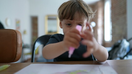 Child playing with art craft at home pressing paint into paper