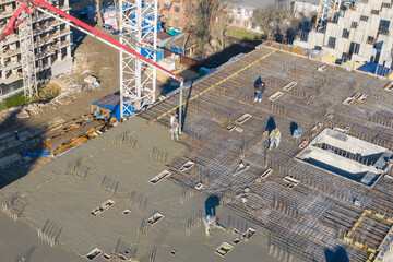 Pouring cement on the floors of residential multi-story building under construction using a...