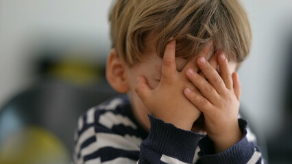 Child covering face with hands OH no