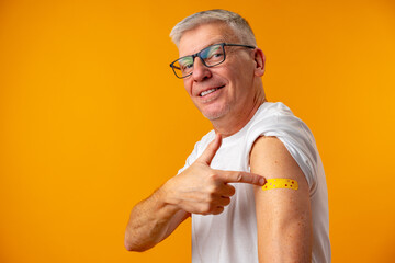Senior man against yellow background recieved corona virus vaccination