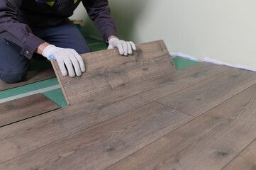The master is laying the laminate. The man is doing the repair of the floor. 