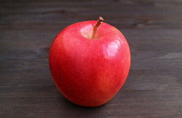 Closeup of a fresh ripe red apple isolated on black wooden backdrop