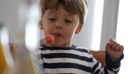 Candid child eating fruit snack at home