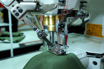 Pro electric sewing machine working. Piece of cloth, needle bar, presser foot, needle plate, feed dog, needle with a thread threaded. Closeup