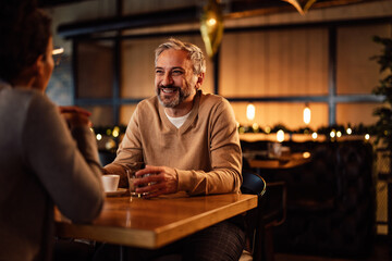 Smiling caucasian adult man, having a drink with his female partner, at a restaurant.
