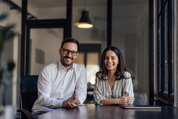 Portrait of happy business partners, smiling for the camera in the office. - 487554081