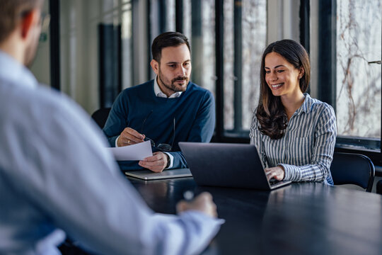 Concentrated caucasian man, looking at his female's partner laptop, while she types.