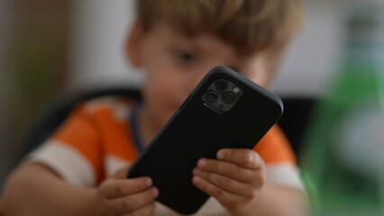 Annoyed little boy using phone upset child holding cellphone