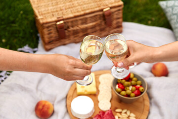leisure, food and drinks concept - close up of hands hands clinking wine glasses above picnic...