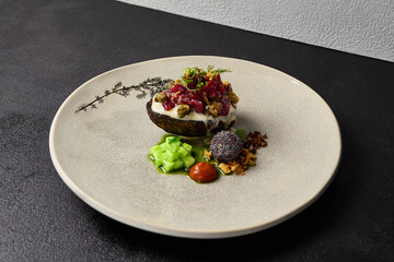 Beef tartare on rye bread with capers, cucumbers, cheese espuma and spices. Meat tartare on handmade ceramic plate. Innovative recipes on modern dishware.