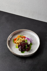 Baked root vegetables in handmade ceramic dishware. Vegan food - caramelized carrot, beetroot and celery on modern crockery. Vegetarian food innovative recipes