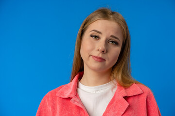 Young woman looking at you with suspicion and accusing over blue background