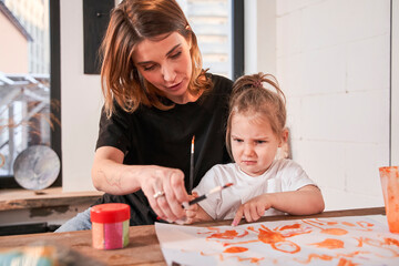Fototapeta premium Girl feeling dissatisfied while drawing with her teacher during the art lesson