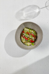 Vegetable ratatouille with zucchini, eggplant and paprika on summer style with hard shadow. Baked vegetables in handmade ceramic bowl. Summer food in modern dishware.