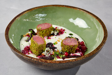 Beef tenderloin in pistachio with cranberry and creamy espuma. Beef medallions in handmade ceramic...