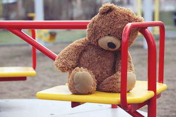 Forgotten Brown Teddy Bear on a Childrens Carousel in an Empty Playground. Concept Childhood,...