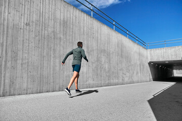 fitness, sport and healthy lifestyle concept - young man running out of tunnel