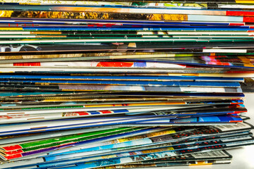 A messy pile of old, colorful magazines on light background.