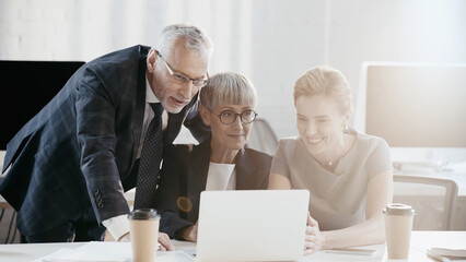 Positive business people sitting near devices and coffee in office