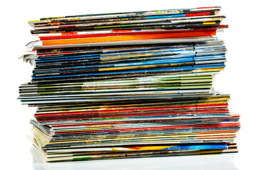A messy pile of old, colorful magazines on light background.