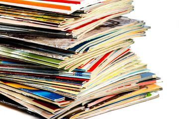 A messy pile of old, colorful magazines on light background.