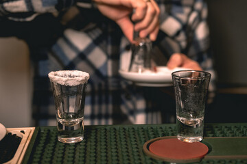 Two empty shot glasses with salt at rim on bar counter for serving tequila
