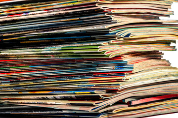 A messy pile of old, colorful magazines on light background.
