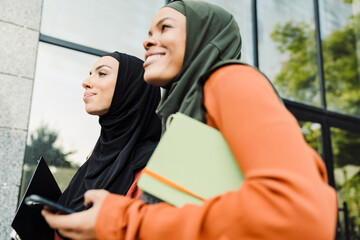 Multiracial muslim women laughing while walking together