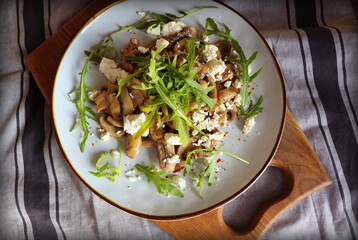Warm mushroom salad with feta cheese and arugula on a linen napkin