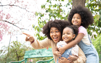 Africa American family doing activity and pointing something on an autumns day in the park. They have bright smiles and happiness.
