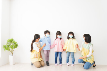 マスクを付けて幼稚園で遊ぶ子どもたちの先生